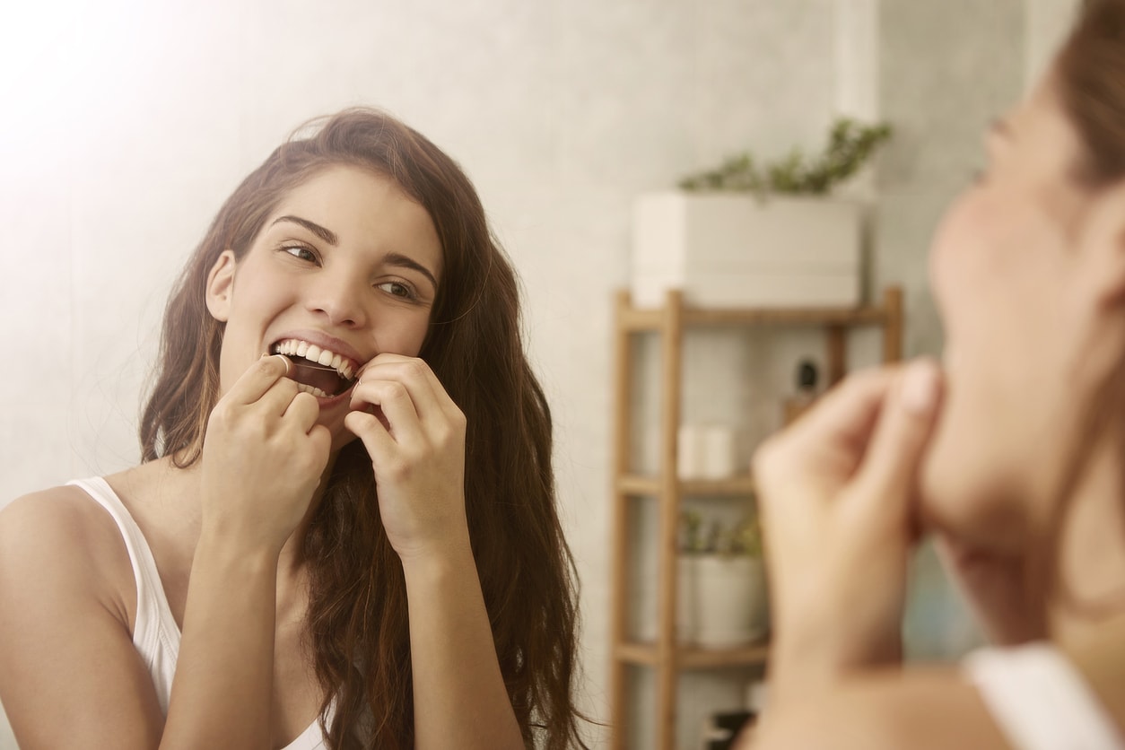 Young adult brunette flossing teeth