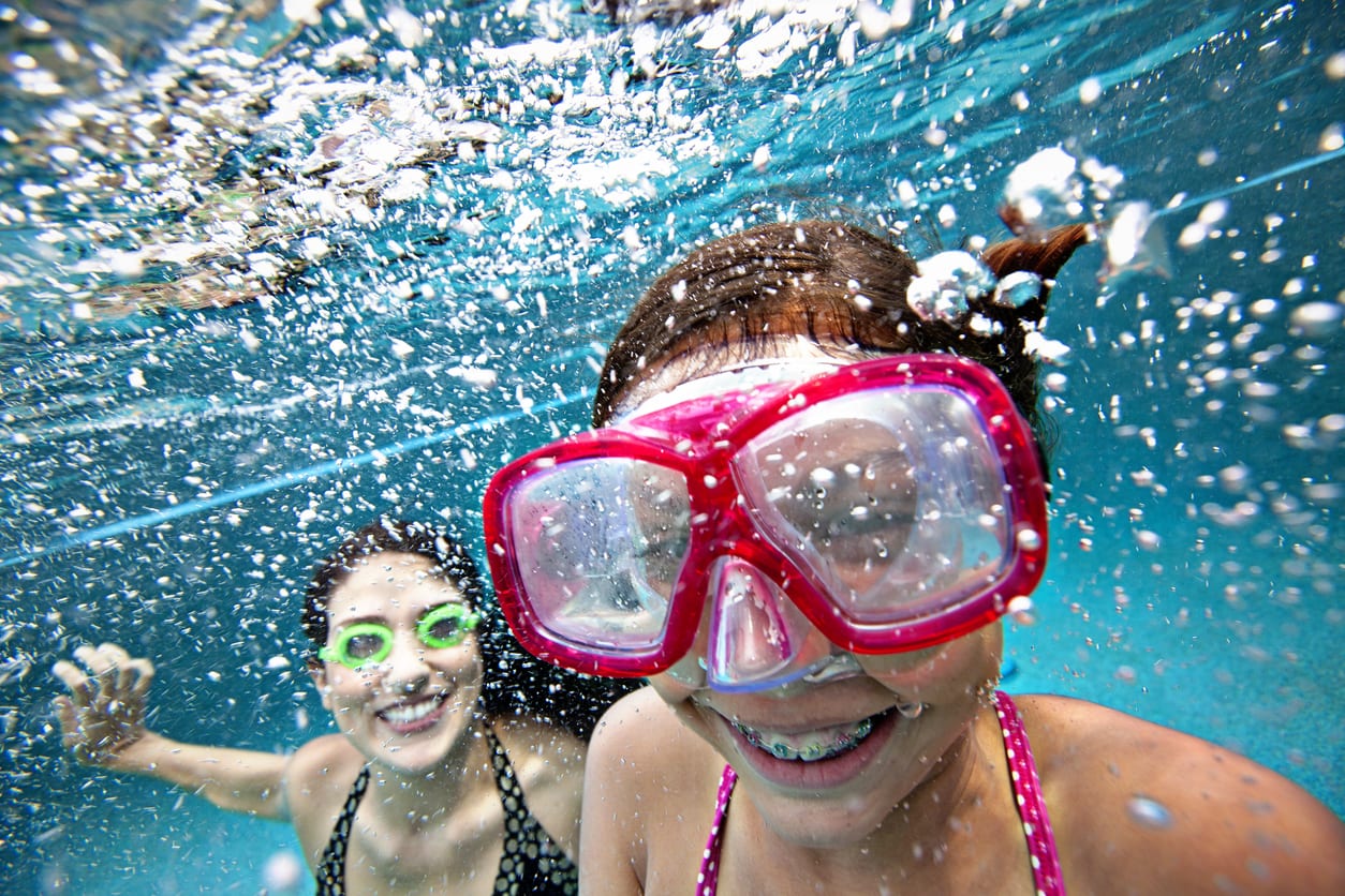 Two girls smiling with braces underwater