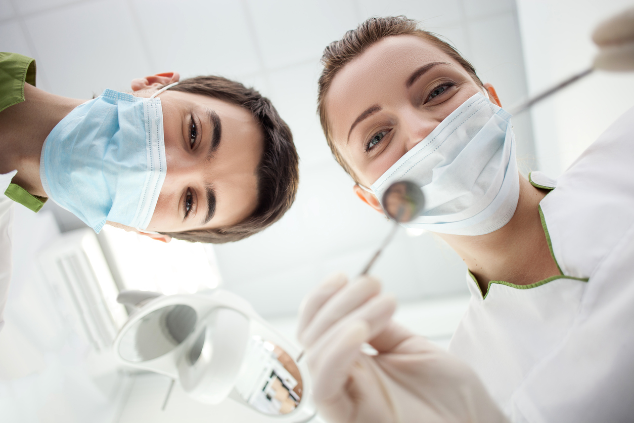 Patient looking up at dentist and dental assistant