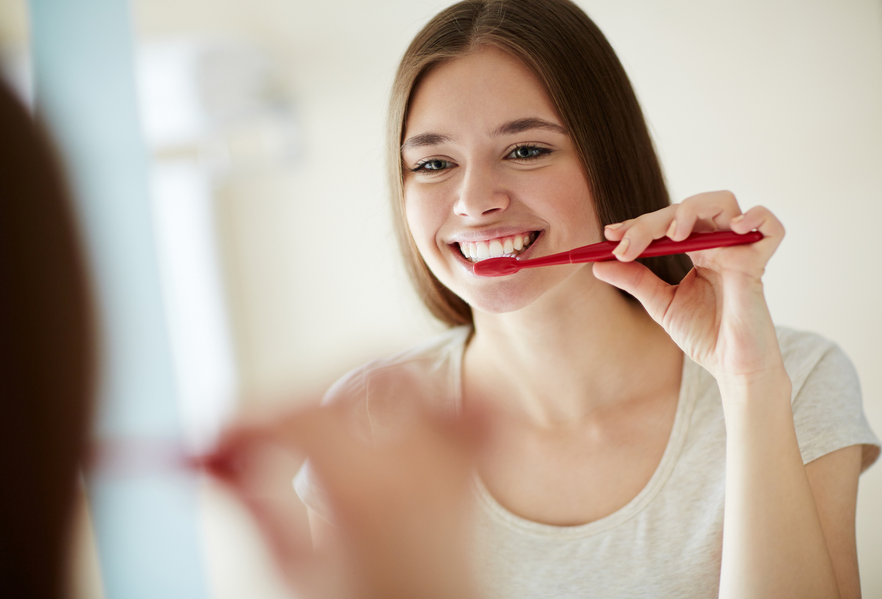 Teen girl smiling while brushing teeth