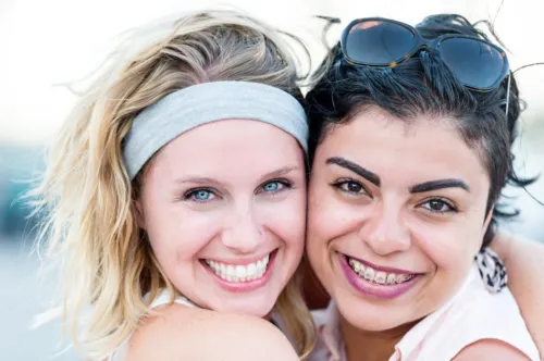 Two young women hugging with one wearing braces