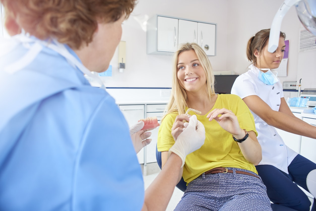 Orthodontist giving teen girl Invisalign retainer