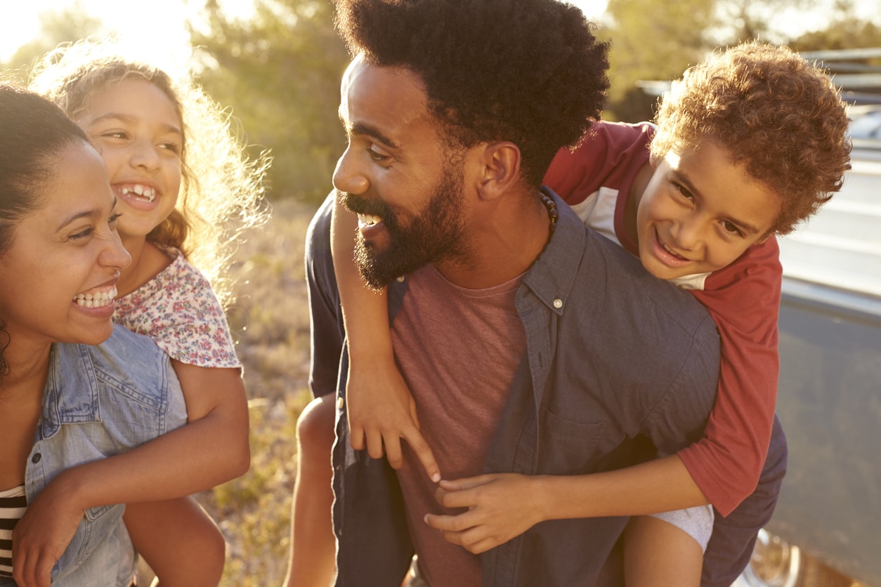 Family of four children on parent's backs