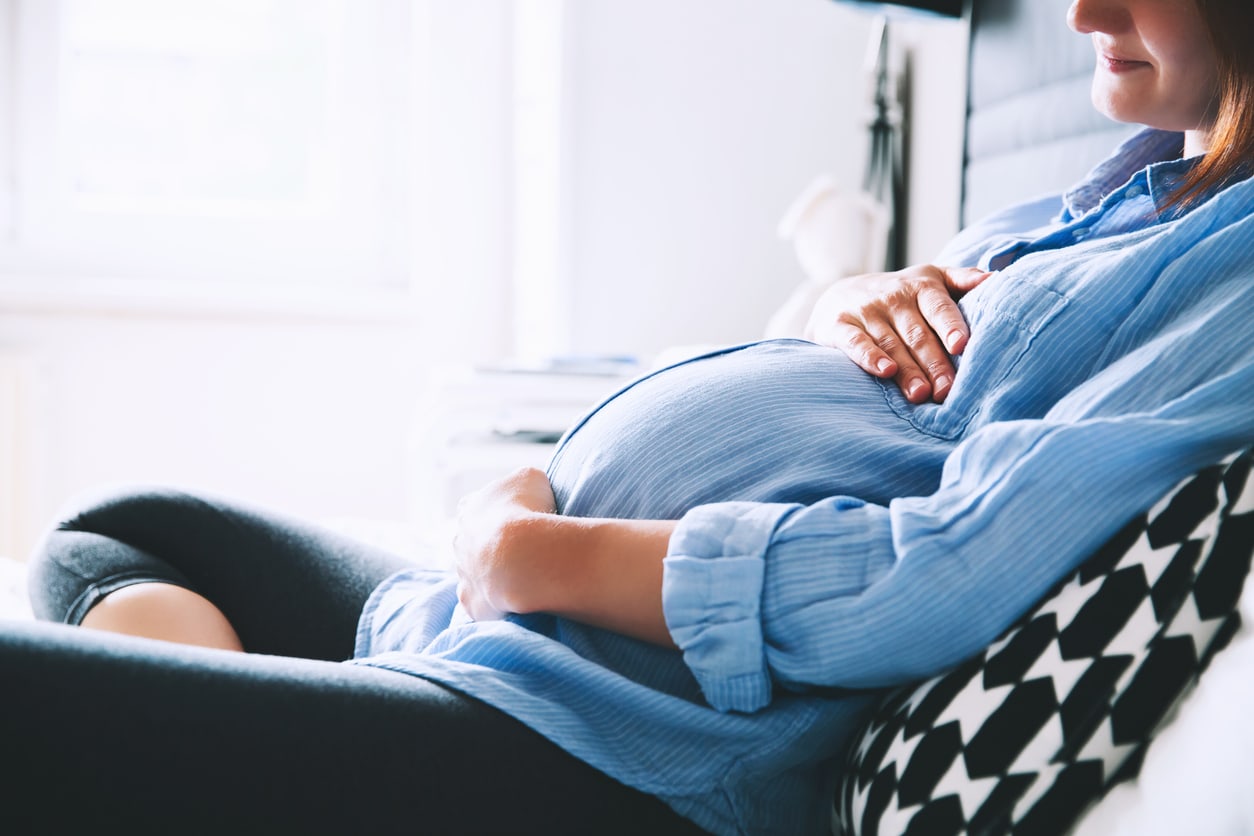 Pregnant adult woman holding stomach