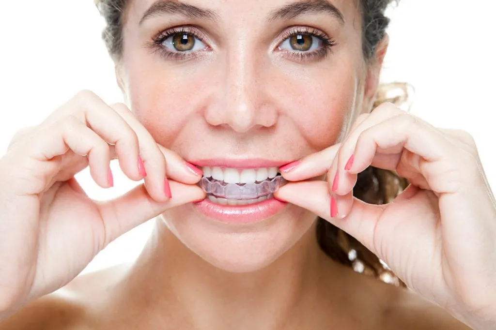 Smiling woman putting in a clear aligner
