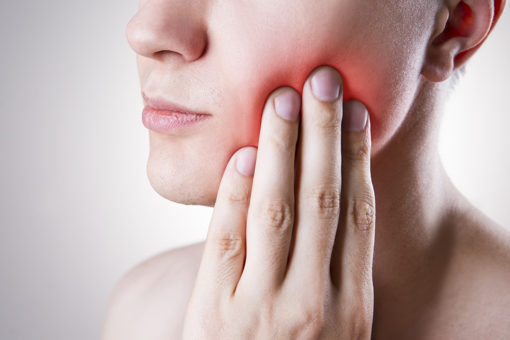 Man holding jaw in pain