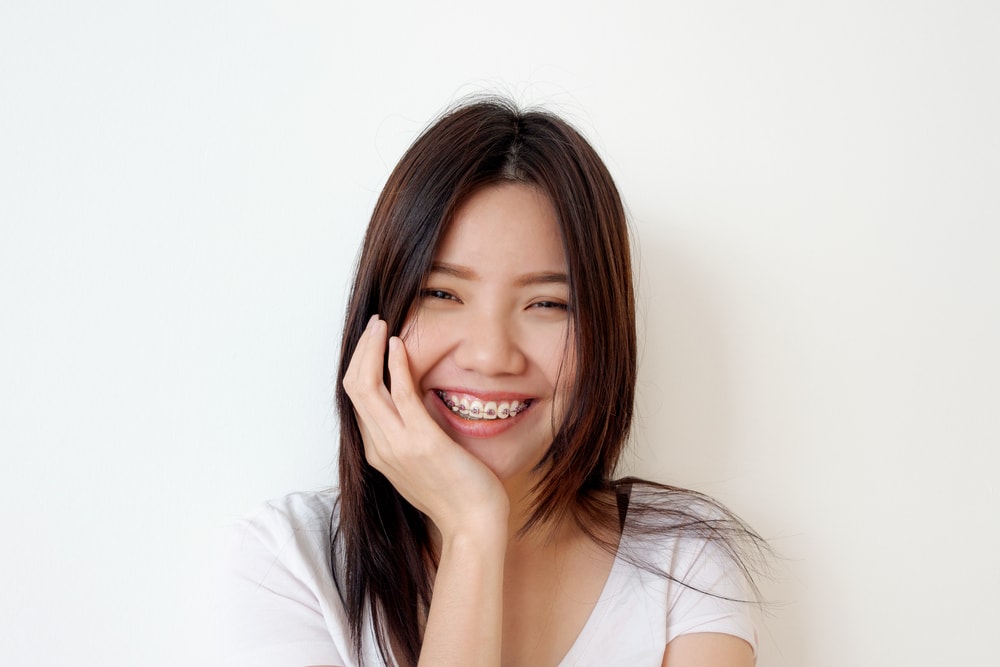 Woman wearing braces holding jaw